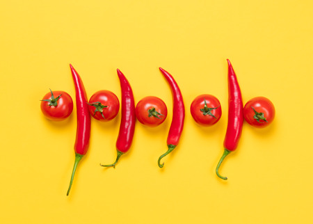 Above view at Chili pepper and tomatoes on yellow background