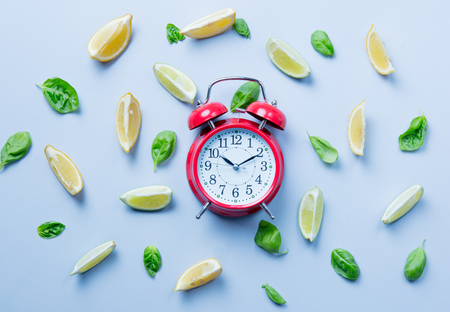 Above view at cutted lemons and limes and alarm clock on grey backgroundの写真素材