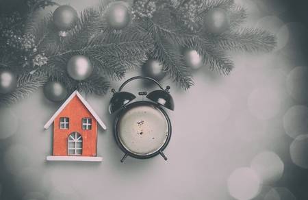 Alarm clock with coffee and toy house with pine branch on violet background.の写真素材