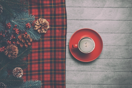 Cappuccino and  pine branch with tartan on wooden table.
