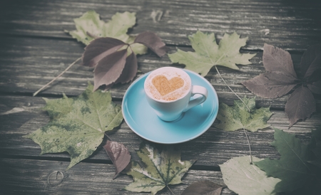 Autumn leaves and coffee cup on wooden table.の写真素材