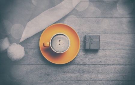 Cappuccino with christmas hat and gift on wooden table. Photo in old color image styleの写真素材