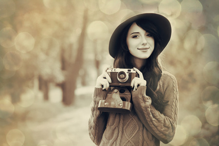 Brunette girl with camera in the park in sunset timeの写真素材
