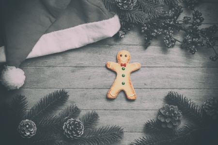 Gingerbread man and christmas hat on wooden table.