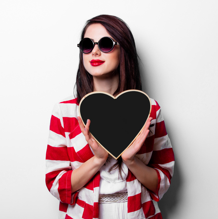 portrait of the beautiful young woman with heart shaped board on the white backgroundの写真素材