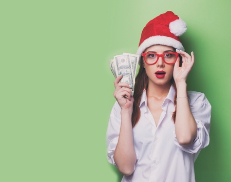 Portrait of a women in christmas hat with money on green background.の写真素材