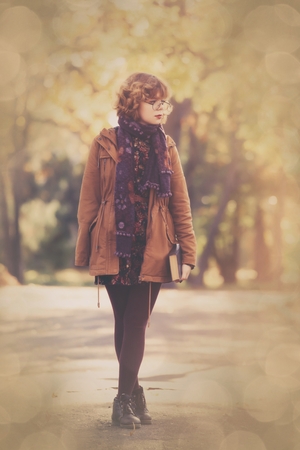Young student girl with book in the autumn parkの写真素材