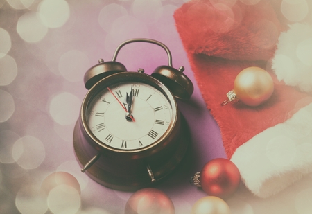 Alarm clock and Santas hat on violet background.の写真素材