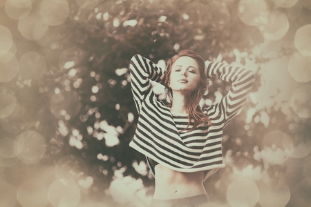 Portrait of a young redhead girl in striped sweater at outdoor in autumn timeの写真素材