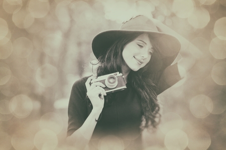 portrait of the beautiful young woman with camera in the parkの写真素材