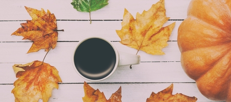Cup of coffee and pumpkin with leafs on white wooden tableの写真素材