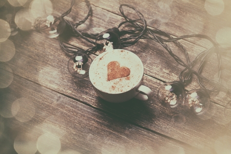 Cup of coffee and electric garland on wooden table.の写真素材