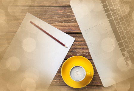 Cup of coffee and paper with laptop computer on wooden backgroundの写真素材