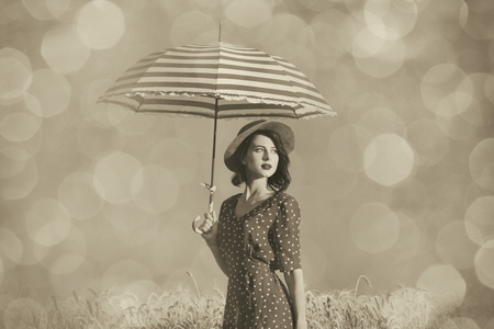 portrait of the beautiful young woman with red umbrella standing in the fieldの写真素材