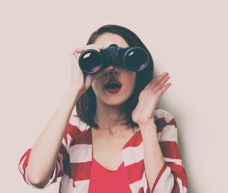 portrait of the beautiful young woman with binocularsの写真素材