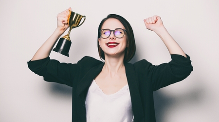 portrait of beautiful young smiling woman with cup trophyの写真素材