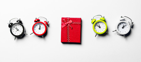 red gift and colorful clocks on the white backgroundの写真素材