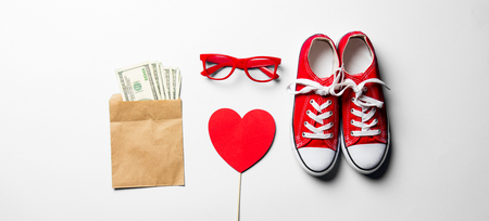 red glasses, gumshoes, money and heart shaped toy on the white backgroundの写真素材