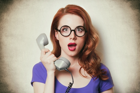 beautiful surprised young woman with retro phone on the wonderful vintage backgroundの写真素材