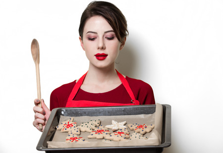 Portrait of young housewife with gingerbread cookie on white backgroundの写真素材