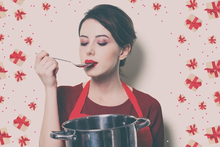 Portrait of young housewife with pan and spoon on white backgroundの写真素材