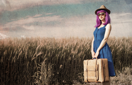 portrait of young beautiful woman with suitcase in the fieldの写真素材