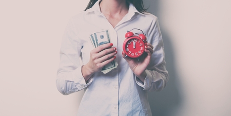 photo of beautiful young woman with clock and moneyの写真素材