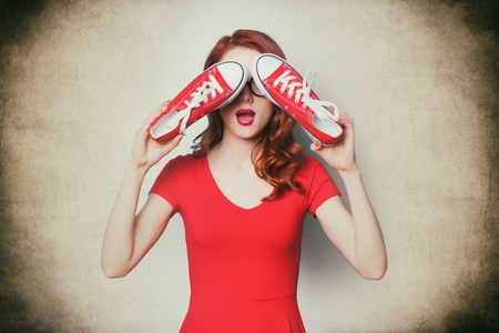 beautiful surprised young woman with gumshoes standing in front of the wonderful vintage backgroundの写真素材