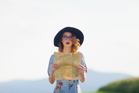 Portrait of young woman in dress with map at autumn countrysideの写真素材