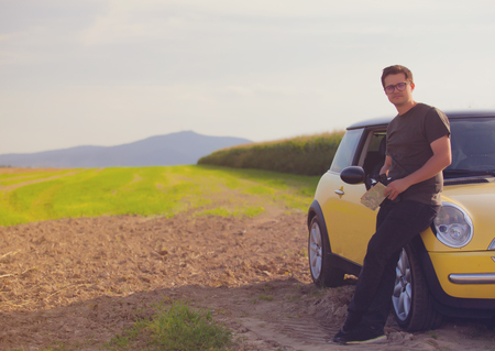 Young man with map standing near a car at countrysideの写真素材