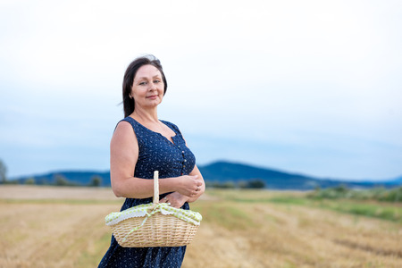 Portrait of senior woman with basket at autumn wheat field. Concept of peope at countrysideの写真素材