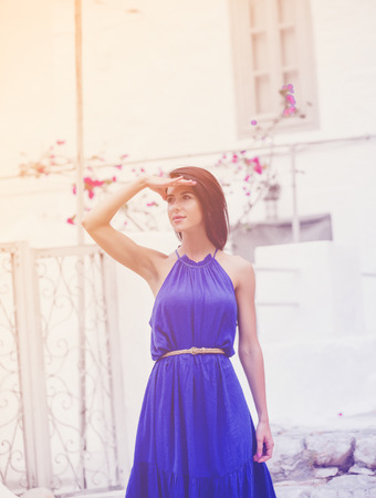 photo of beautiful young woman standing on the stairs near the house in Greeceの写真素材