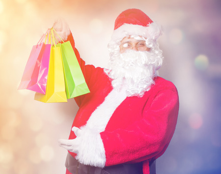 Funny Santa Claus have a fun with shopping bags on blue backgroundの写真素材