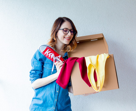 young redhead woman in jeans shirt standing on white wall with moving box. European ethnicityの写真素材