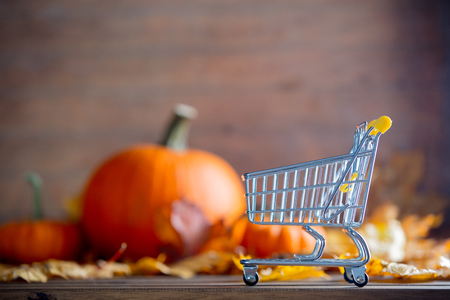 maple leaves and pumpkins with supermarket cart on wooden table.の写真素材
