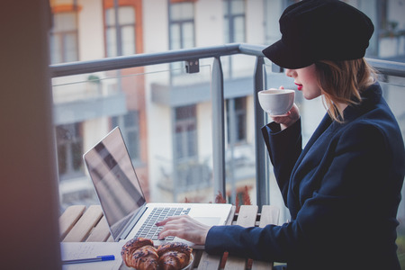 Beautiful young businesswoman working on laptop while sitting outdoors at home. Concept of work with startup businessの写真素材