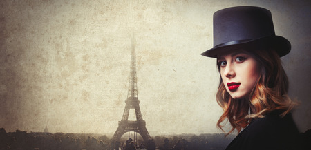 Style and mystique redhead girl in top hat on Parisian Eiffel Tower background の写真素材