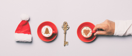 Red Santa Claus hat and cup of coffee on grey backgroundの写真素材