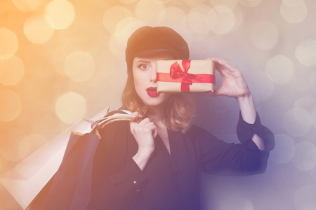 Style redhead girl in hat with shopping bags and gift box on grey backgroundの写真素材