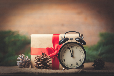 Christmas gift and pine cones with Alarm clock on jute background