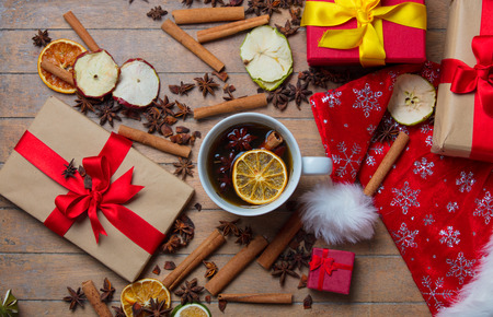 Christmas gifts, cinnamon, star anise and cup of tea on wooden backgroundの写真素材