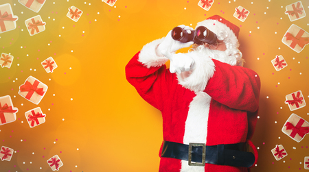 Funny Santa Claus holding binoculars on yellow backgroundの写真素材