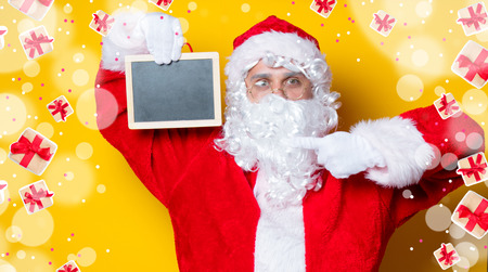 Funny Santa Claus holding black board on yellow backgroundの写真素材
