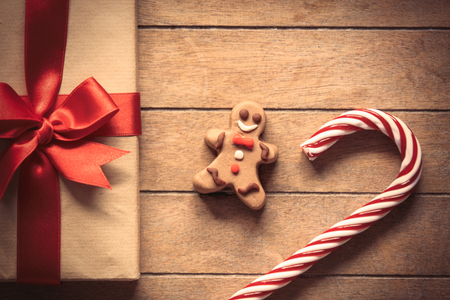 Sweet lollipop with gingerbread man and Christmas gift box on wooden backgroundの写真素材