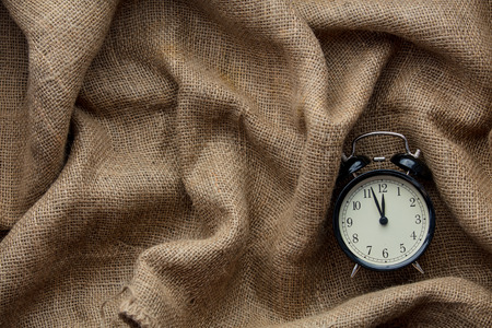 Vintage alarm clock on jute background. Above view 