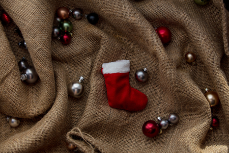 Christmas sock and baubles in Santa Claus hat on jute backgroundの写真素材