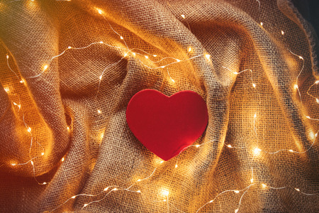 Heart shape gift box and Fairy Lights around on jute background. Above point of view の写真素材