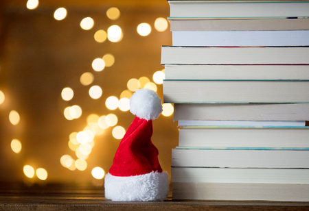 Christmas gift box, Santa Claus hat and pile of books with fairy lights on backgroundの写真素材