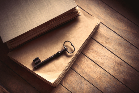 Vintage key and old books on wooden table. Photo in old image color styleの写真素材