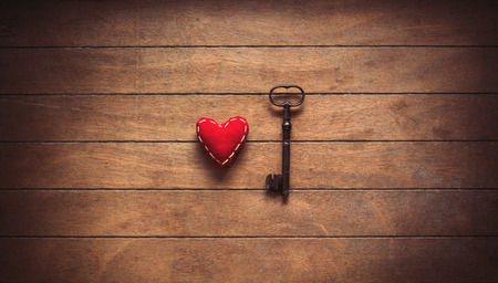 Heart shape and metal classic key on old wooden background. Image in old color styleの写真素材